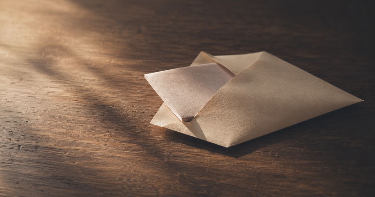 封を切った封筒から、二つ折りの紙が半分だけ出ている